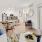 A modern open-concept apartment with light wood flooring, white walls, stylish furniture, and pendant lighting over the kitchen island