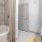 A bathroom with a tiled bathtub, beige shower curtain, granite countertop vanity, and a gray door